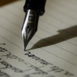 A calligraphy pen mid-sentence on a white piece of paper